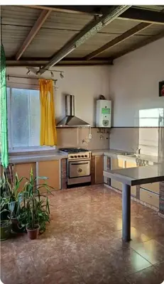 a large kitchen with a stove and a table at Depto wifi rápido con grandes espacios verdes in Río Tercero