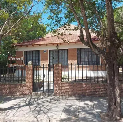 a brick house with a fence and a tree at Hosteria Rivadavia in Mina Clavero