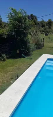 a blue swimming pool in a yard with a tree at Casa los nonos in Cavalango