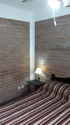a bedroom with a bed and a brick wall at Postal Serrana 2 in Villa Cura Brochero