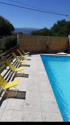 a row of yellow lounge chairs next to a swimming pool at Postal Serrana 2 in Villa Cura Brochero