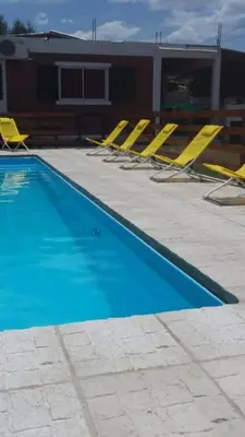 a row of yellow chairs and a swimming pool at Postal Serrana 2 in Villa Cura Brochero
