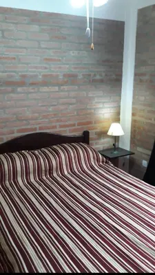 a bed in a bedroom with a brick wall at Postal Serrana 2 in Villa Cura Brochero