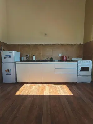 a kitchen with white appliances and a wooden floor at Green Valley Retreat in Villa General Belgrano