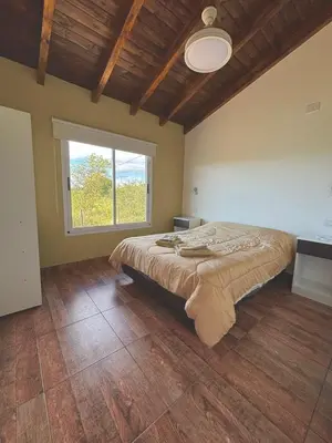 a bedroom with a large bed with a large window at Green Valley Retreat in Villa General Belgrano