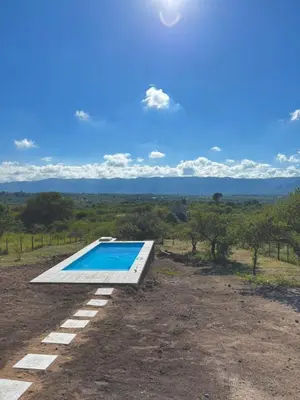a swimming pool in the middle of a field with trees at Green Valley Retreat in Villa General Belgrano