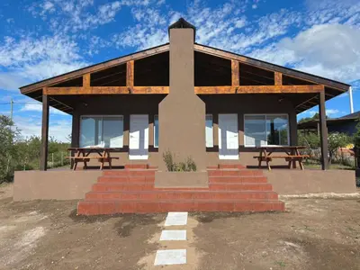 a building with two picnic tables in front of it at Green Valley Retreat in Villa General Belgrano