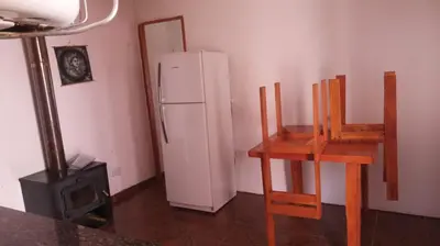 a kitchen with a white refrigerator and two wooden chairs at casitadearminda-II in Villa de Las Rosas