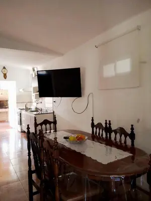 a dining room table with a tv on the wall at Villa Carlos Paz Inn in Villa Carlos Paz