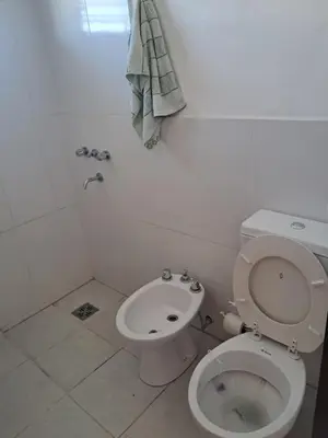 a white bathroom with a toilet and a sink at Departamento Alta Gracia in Alta Gracia