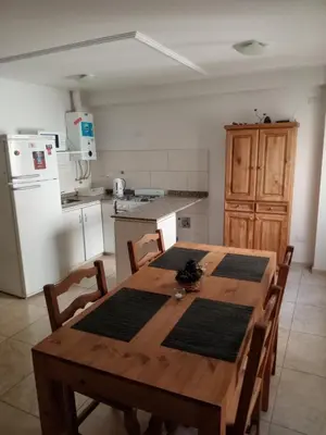 a kitchen with a wooden table with chairs and a refrigerator at Departamento en Gral paz in Cordoba