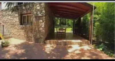 a stone house with a porch with a wooden roof at Chalet de piedra y madera in Cordoba