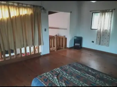 an empty living room with wooden floors and curtains at Chalet de piedra y madera in Cordoba