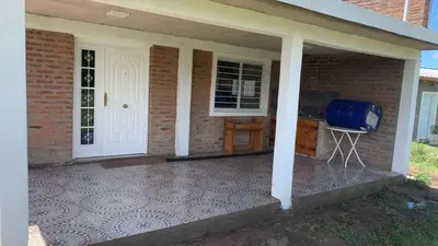 a brick house with a front porch with a white door at Casa para 5 personas a 1 cuadra del río los Reartes in Villa Ciudad Parque
