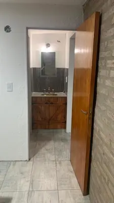 a bathroom with a sink and a wooden door at Casa para 5 personas a 1 cuadra del río los Reartes in Villa Ciudad Parque