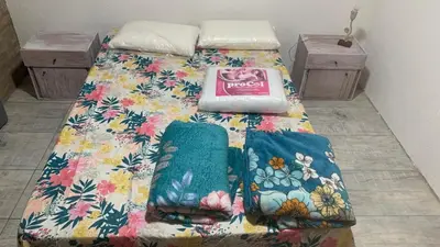 a bed with a floral bedspread on top of it at Casa para 5 personas a 1 cuadra del río los Reartes in Villa Ciudad Parque