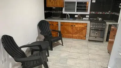 a kitchen with two chairs and a sink and a stove at Casa para 5 personas a 1 cuadra del río los Reartes in Villa Ciudad Parque