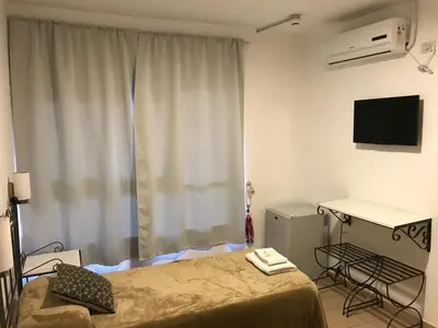a room with a bed and a desk and a television at Faro del Parque in Cordoba