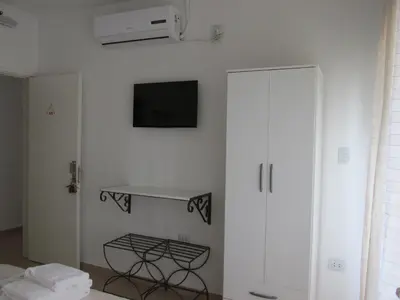 a bedroom with a white wall with a tv on the wall at Faro del Parque in Cordoba