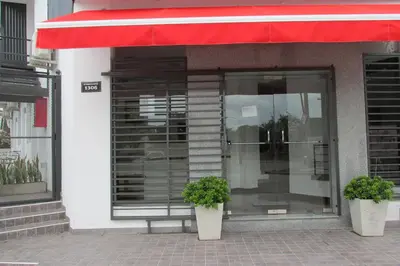 a store front with a red awning and two plants at Faro del Parque in Cordoba