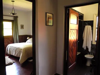 a bedroom with a bed and a bathroom with a sink at Hotel San Huberto Tenis in Nono