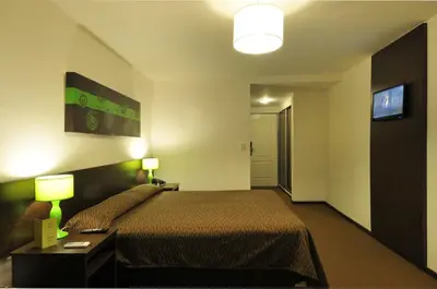 a hotel room with a bed and a flat screen tv at Los Sauces Hotel & Spa in Villa Carlos Paz