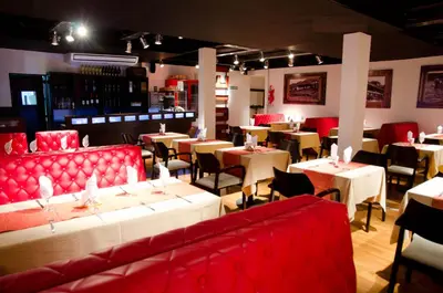 a restaurant with red chairs and tables and tablesearcher at Los Sauces Hotel & Spa in Villa Carlos Paz
