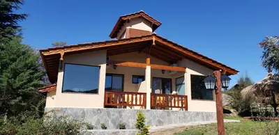 a house with a wrap around porch at Aires Serranos - Suites in La Cumbrecita