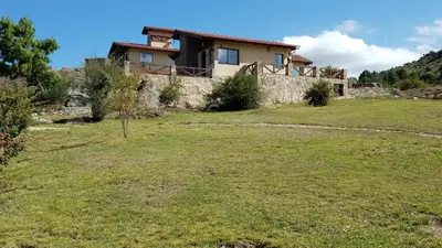 a house on a hill with a grass yard at Aires Serranos - Suites in La Cumbrecita