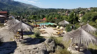 a resort with chairs and umbrellas and a pool at Aires Serranos - Suites in La Cumbrecita