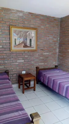 two beds in a room with a brick wall at Cabañas El Molinillo in Nono