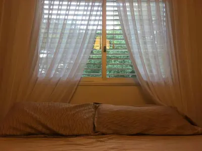 a bedroom with a bed and a window with white curtains at Quebrada Mansa in Nono