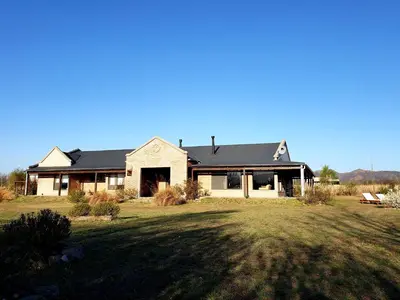 a house with a black roof on a grass field at Refugio Del Guira Guira in Los Reartes