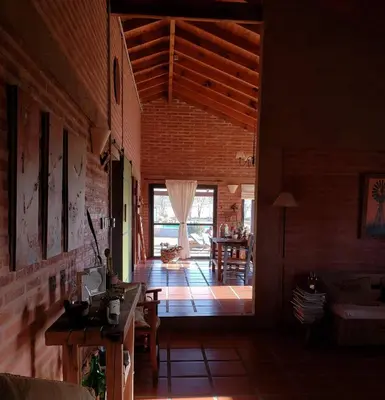 a living room with a large window and a brick wall at Refugio Del Guira Guira in Los Reartes