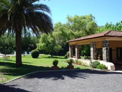 a house with a palm tree and a porch at Las Acacias - Posada de Campo in Villa General Belgrano