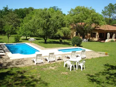 a yard with a pool with chairs and a table at Las Acacias - Posada de Campo in Villa General Belgrano