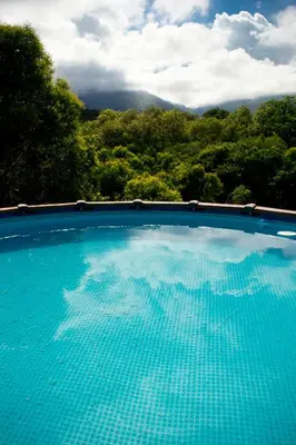 a blue swimming pool with trees in the background at Tierra Sagrada Eco Lodge in La Población