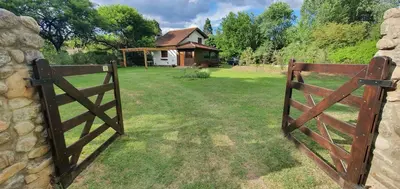 a wooden gate leading to a yard with a house at Cabaña Odanak in Villa General Belgrano