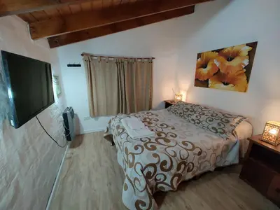 a bedroom with a bed and a flat screen tv at Cabaña Odanak in Villa General Belgrano