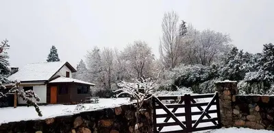 a house with a fence and a gate in the snow at Cabaña Odanak in Villa General Belgrano