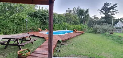 a wooden deck with a picnic table and a swimming pool at Cabaña Odanak in Villa General Belgrano