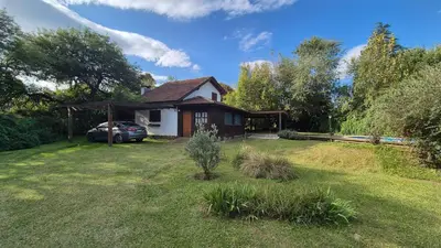 a house with a car parked in the yard at Cabaña Odanak in Villa General Belgrano