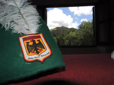 a green pillow with a crest on it with a window at Cabaña Odanak in Villa General Belgrano