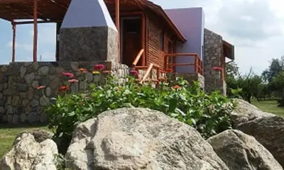 a house with a stone wall and flowers in front of it at Cabañas Yanasuy in Merlo