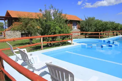 a swimming pool with chairs and a house at Cabañas Yanasuy in Merlo