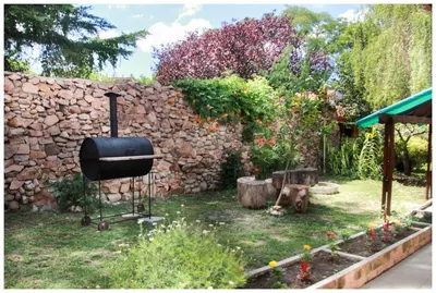 a backyard with a grill and a stone wall at El Camino Hostel in Mina Clavero