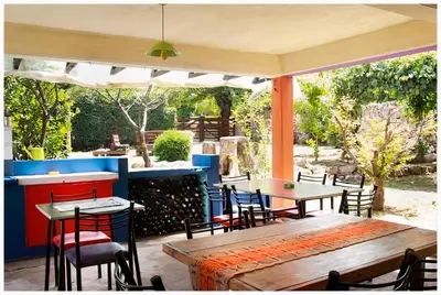 a patio with tables and chairs under an umbrella at El Camino Hostel in Mina Clavero