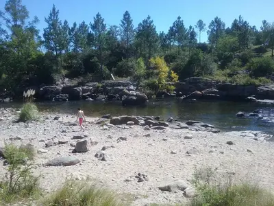 a person standing on a beach next to a river at Cabañas Nueve Lunas in Santa Rosa de Calamuchita