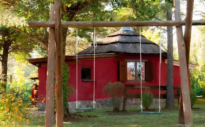 a red house with a straw roof at Cabañas Nueve Lunas in Santa Rosa de Calamuchita