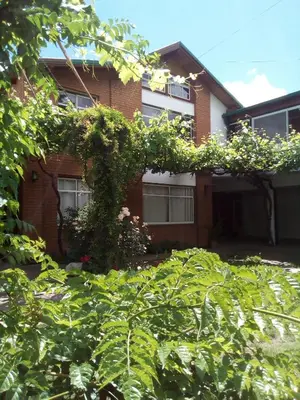 a red brick house with lots of green leaves at Hosteria Nilo Azul in Mina Clavero